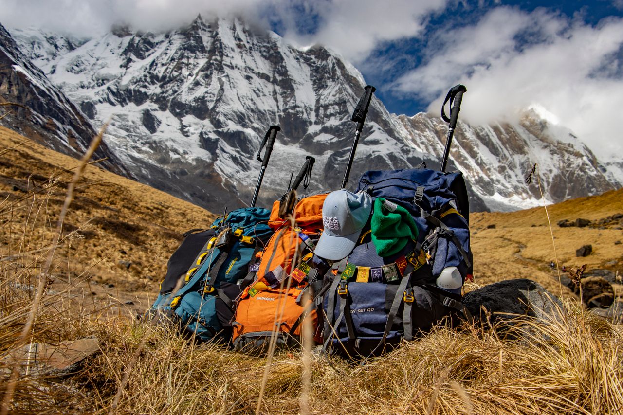 Mastering the First Impression: Your intriguing post title goes here Backpacks rest at Annapurna's base under the snowy peaks, capturing trekking adventure in Nepal.