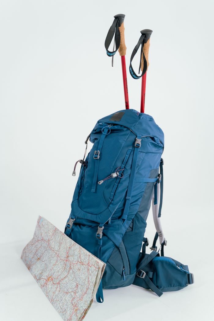 About Blue backpack with trekking poles and map, ready for an adventure.